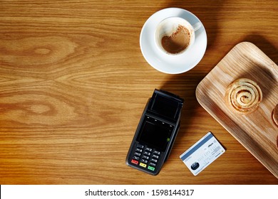 Lifestyle Photograph Of EFT Credit Card/debit Card Machine Sitting On A Shop Counter Photographed Overhead With Credit Card, Espresso Coffee And Tray Of Pastries