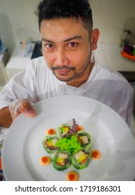 Lifestyle Portrait Of Asian Home Cook Man Or Professional Chef Cooking In Clean Kitchen Showing Traditional Japanese Sushi Roll Dish Happy And Proud In Japan Food Culture