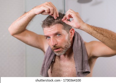 Lifestyle Portrait Of Mid Adult Attractive Concerned And Upset Man At Home Bathroom Searching And Finding Gray Hair Looking At The Mirror Worried About Aging 