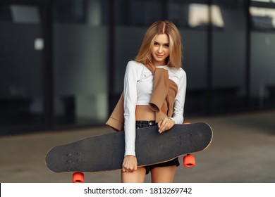Lifestyle portrait of young woman with longboard. High quality photo