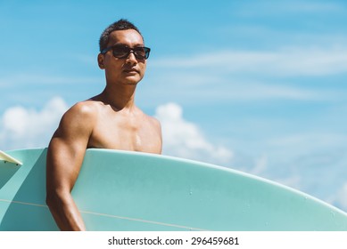 Lifestyle series : Asian man holding surf board looking at camera with color effect