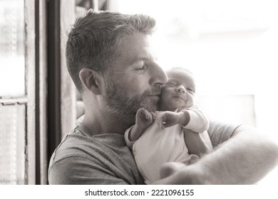 Lifestyle Shot In Black And White Of Young And Happy Man Holding Tenderly In His Arms Adorable Newborn Baby Girl  In Father And Daughter Love And Care Concept