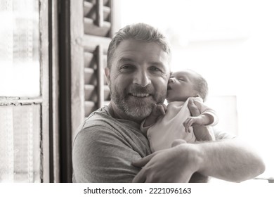 Lifestyle Shot In Black And White Of Young And Happy Man Holding Tenderly In His Arms Adorable Newborn Baby Girl  In Father And Daughter Love And Care Concept