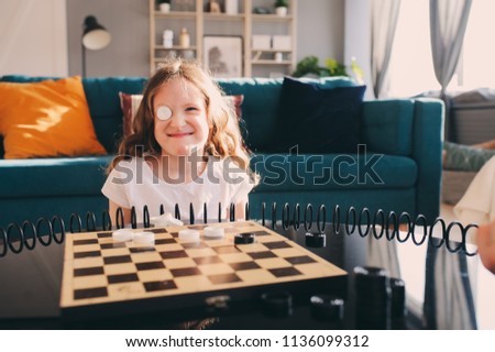 lifestyle shot of smart kid girl playing checkers at home. Board games for kids concept, candid series with real people in modern interior