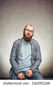 lifestyle successful young man with glasses , beard, fashionable denim jacket looking forward,male portrait in the Studio on a uniform background