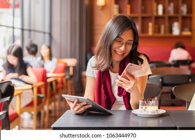 Lifestyle, Technology  Concept - Asian woman using app on a smart phone while relaxing in cafe during free time with copy space. 