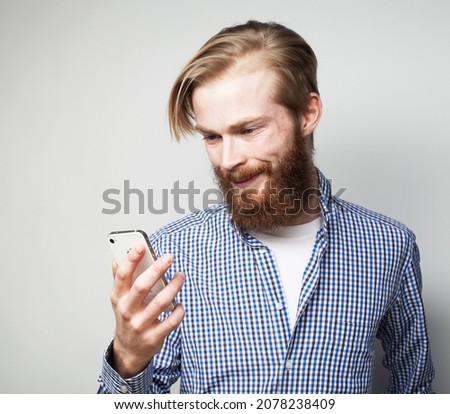 lifestyle, tehnology business and people concept: Young business man using mobile phone. Redhair beardman smiling over grey background. Stock photo © 