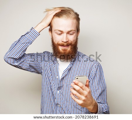 lifestyle, tehnology business and people concept: Young business man using mobile phone. Redhair beardman smiling over grey background. Stock photo © 