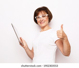 Lifestyle, Tehnology And Old People Concept: Elderly Woman Holding An Ipad And Showing Thumbs Up Sign Over White Background