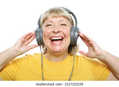 Lifestyle, tehnology and people concept: Funny old lady wearing yellow shirt listening music with headphones over white background
