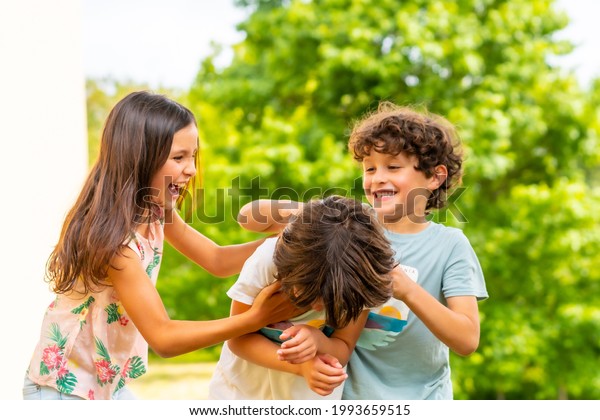 Lifestyle of three brothers smiling and playing\
together in a park, friends and brothers enjoying as a family,\
tickling each other