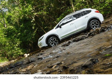 Lifestyle, travel on summer vacation with SUV 4wd adventure and exploration nature find scenery in forest, discovery white car drives into stream crossing river. Kaeng Krachan, Phetchaburi, Thailand
