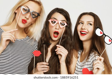 lifestyle,friendship and people concept: Three young women holding paper party sticks over white background