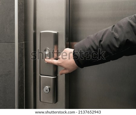Lift button pressing. Elevator buttons pushing, forefinger pressing on down button, finger touching metal control panel on wall