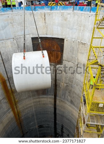 Lift the drill head of tunnel boring machine  into the construction shaft  using a crane. Engineer and technician to control the method of lifting machinery underground.