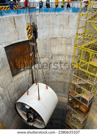 Lift the drill head of tunnel boring machine  into the construction shaft  using a crane. Engineer and technician to control the method of lifting machinery underground.