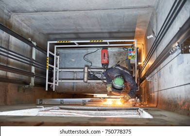 lift worker welding elevator fasteners in lift shaft - Powered by Shutterstock