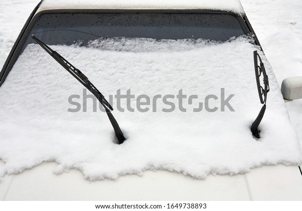 Lifted car\
wipers on the snow covered\
windshield.