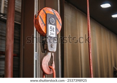 The lifting device features a pulley system designed for safely elevating heavy loads in an industrial workshop setting.