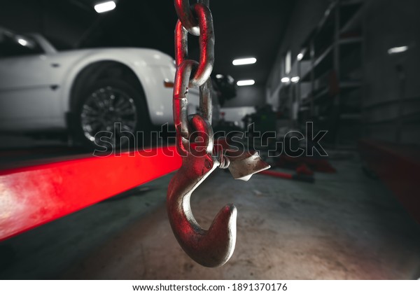 Lifting the\
engine crane at car service. Close-up. Details, selective focus.\
Copy space. Vehicle in the\
background