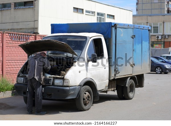 Lifting the\
hood, the driver repairs the truck on the street, Podvoysky Street,\
St. Petersburg, Russia, June\
2022