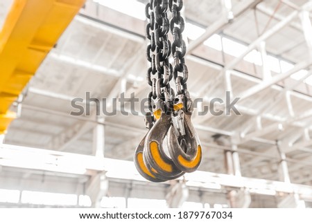 Lifting mechanism iron chain with a hook of an overhead crane on the background of an industrial enterprise or factory