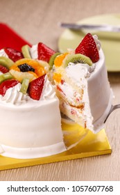 Lifting A Slice Of White Cake Topped With Fresh Fruit.