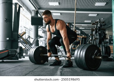 Lifts a barbell. Strong muscular man is working out in the gym. - Powered by Shutterstock