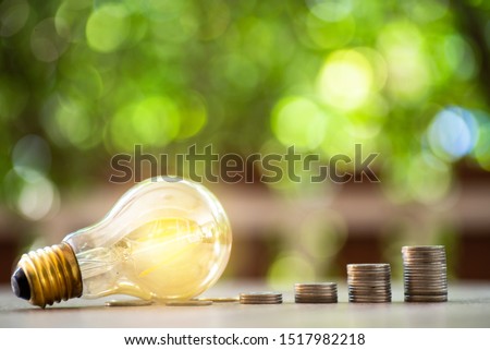Ligh bulb and coin money stack on wood - Concept of saving money, gain wealth, increase profits.