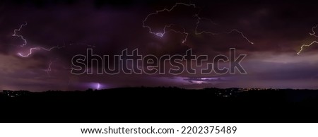 Lighning bolt over night sky in central europe. Huge lightning in a purple clouds at over a night city. Night storm with lightnings.