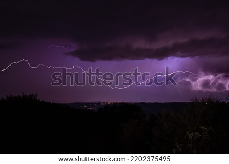 Lighning bolt over night sky in central europe. Huge lightning in a purple clouds at over a night city. Night storm with lightnings.