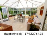 A light and airy furnished sun room (conservatory) with view of trees in the background 