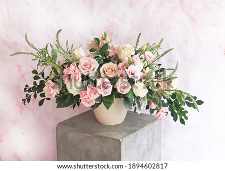     Light airy pink white and green floral arrangement of fresh flowers like roses, spray roses and fresh greenery, marble pink and white background, white vase, Mother's Day.                         