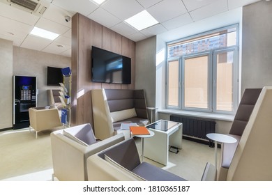 Der helle und luftige Wartebereich für die Gäste mit beigefarbenen Ledersofas, Sesseln, einem Couchtisch und einem Fernseher