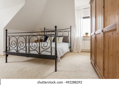 Light Bedroom With Wooden Wardrobe And Bed With Decorative Metal Frame