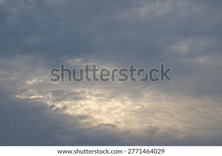 LIGHT BEHIND THINNING LAYER OF GREY CLOUD