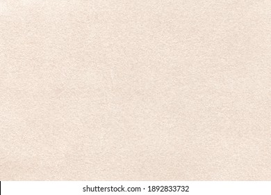Light beige matte background of suede fabric, closeup. Velvet texture of seamless cream textile, macro. Structure of brown felt canvas backdrop.