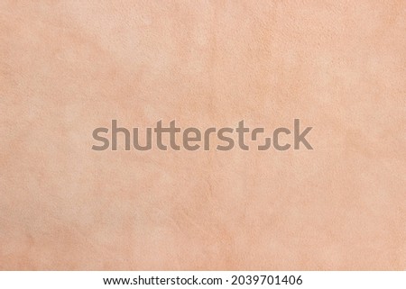 Light beige matte background of suede fabric, closeup. Velvet texture of seamless sand leather. Soft beige leather texture with print as background.