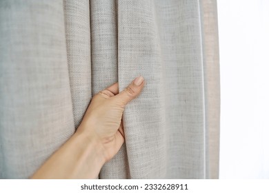 Light beige sand linen natural curtains on window, close-up of hand touching curtains - Shutterstock ID 2332628911