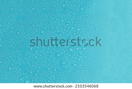 Light blue background with large and small drops of water in natural light. The texture of a water drop on a colored background is a top view.