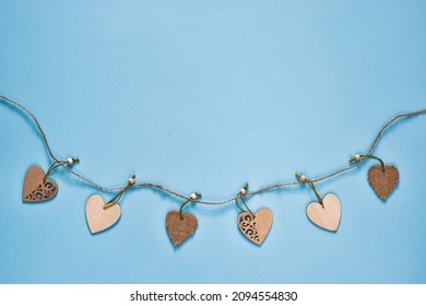 Light blue background with wood hearts garland. Valentines card. Valentines day concept