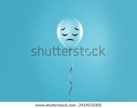 Light blue balloon with sad face on light blue background