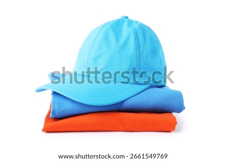 Light blue baseball cap and stack of folded t-shirts isolated on white. Mockup for design