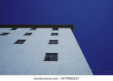 A light blue building in Europe,  minimalistic architecture. Blue sky on a sunny day. Windows reflecting the light from the sun, the game of shadows and light - Powered by Shutterstock