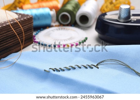 Light blue cloth with sewing thread and stitches on table, closeup