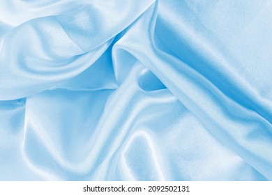Light blue color silk wavy textile pattern as a smooth textured background. Sky colored soft satin fabric drapery