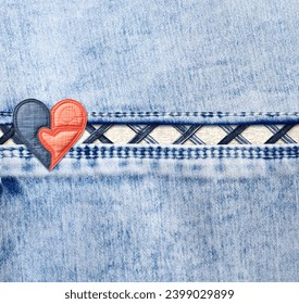 Light blue denim background with a seam and felt heart. Suqare blue color denim jeans fabric texture with heart-shaped textile patch. Valentine's day denim backdrop. Copy space for text