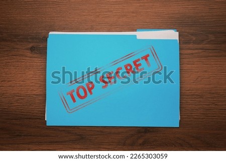 Light blue file with documents and Top Secret stamp on wooden table, top view
