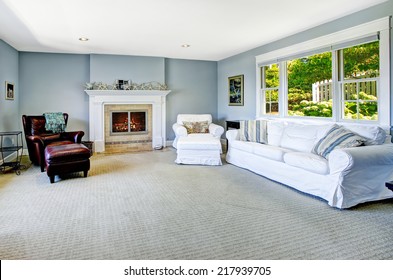 Light Blue Living Room With White Sofa, Armchair And Leather Chair And Cozy Fireplace