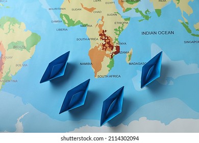 Light Blue Paper Boats On World Map, Flat Lay